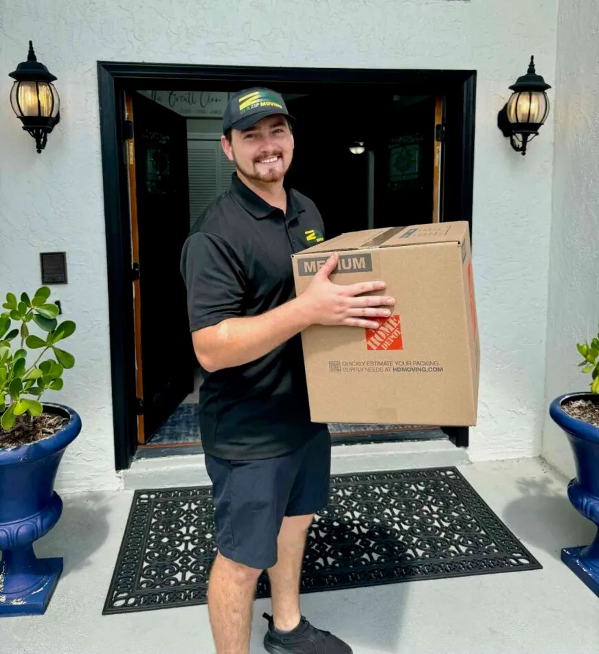 An In A Zip Moving crew member carrying a moving box at a customer's front door
